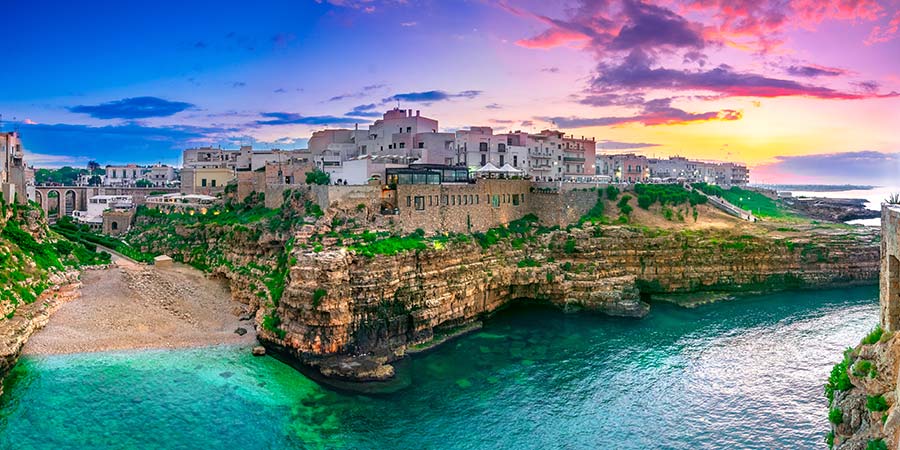 Traditional Italian houses sit next to the rugged coastline of Puglia. 