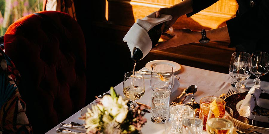 Staff onboard the Royal Scotsman serve drinks with the evening meal.